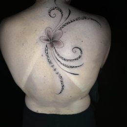 Fleur et volutes en noir et gris sur le haut du dos