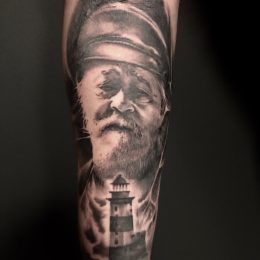 Portrait d'homme et phare en noir et gris sur le bras