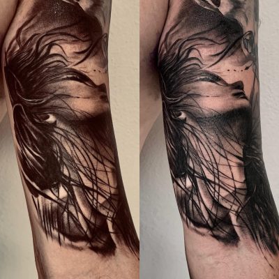 Visage de femme et plumes en noir et gris sur le bras