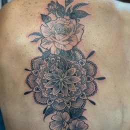 Mandala et roses en noir et gris sur le haut du dos
