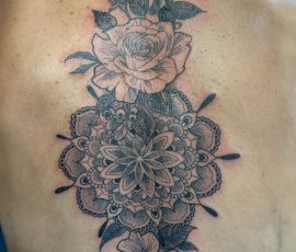 Mandala et roses en noir et gris sur le haut du dos