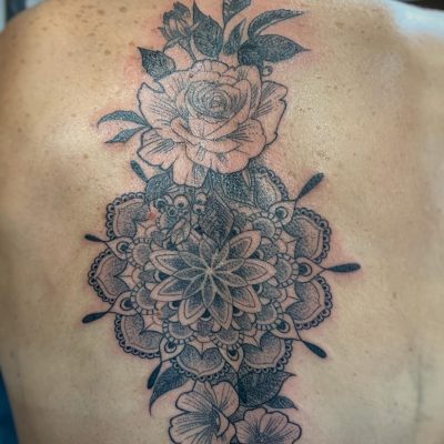 Mandala et roses en noir et gris sur le haut du dos