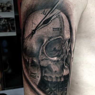 Crâne et horloge en noir et gris sur le bras