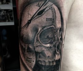 Crâne et horloge en noir et gris sur le bras