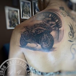 Moto en réalisme noir et gris sur l'omoplate