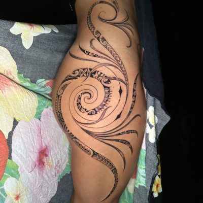 Volutes polynésiennes en noir et gris sur la hanche et la cuisse