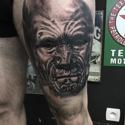 Masque maori en noir et gris sur la cuisse