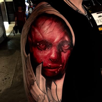 Visage encapuchonné en rouge et noir sur le bras