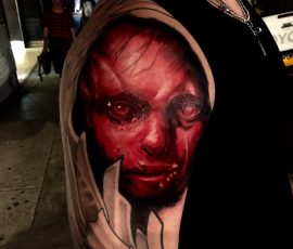 Visage encapuchonné en rouge et noir sur le bras