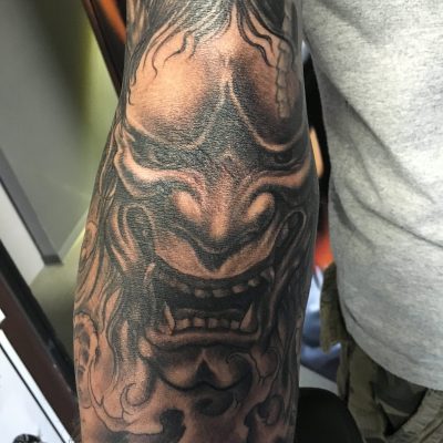 Masque hannya japonais en noir et gris sur l'épaule