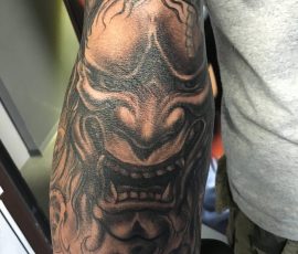 Masque hannya japonais en noir et gris sur l'épaule