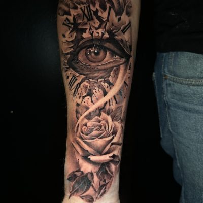Œil et roses en noir et gris sur l'avant-bras