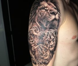 Lion et roses en noir et gris sur l'épaule, vue de face