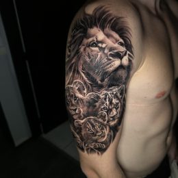 Lion et roses en noir et gris sur l'épaule