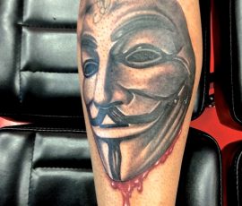 Masque de Guy Fawkes sur le mollet, avec lettrage
