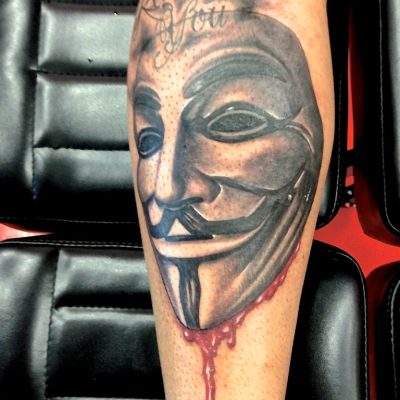 Masque de Guy Fawkes sur le mollet, avec lettrage