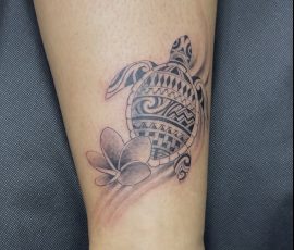 Tortue et fleurs de frangipanier en noir et gris sur la cheville