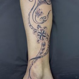 Volutes polynésiennes, tortue et fleurs sur la jambe